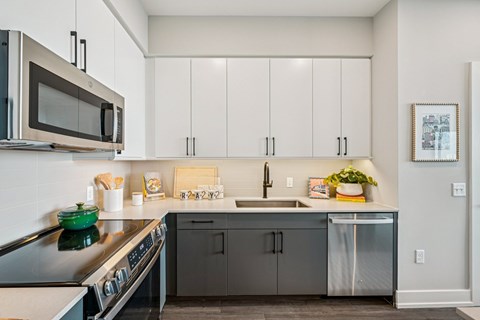 A modern kitchen with a green stove top and white cabinets.