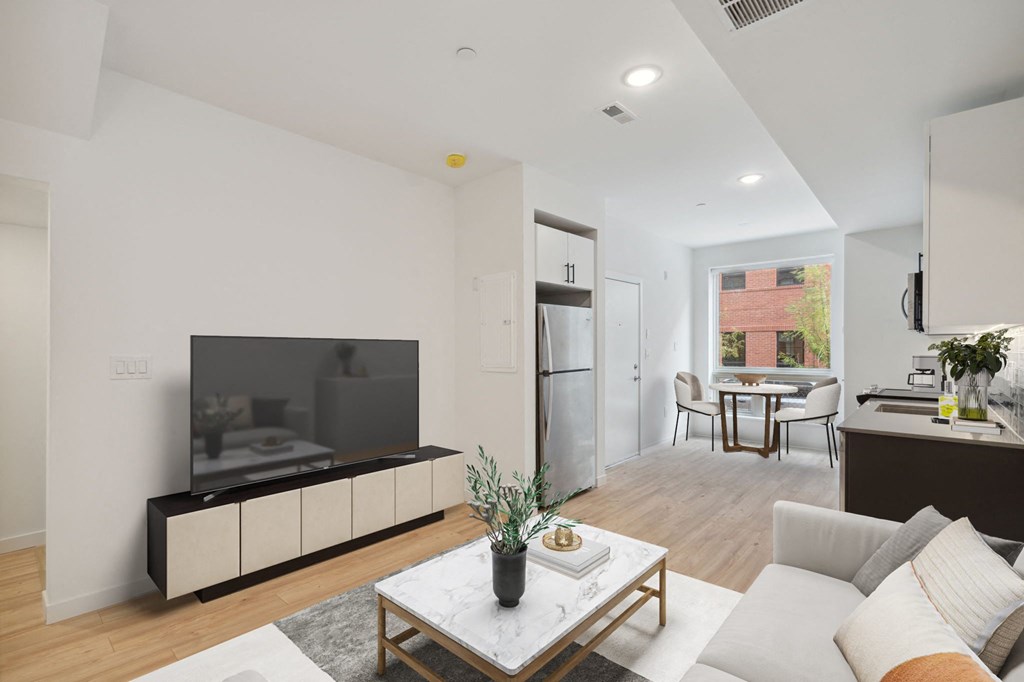 Contemporary living room with a neutral color scheme, featuring a sleek TV unit, comfortable white sofa, and an integrated dining area visible in the background.