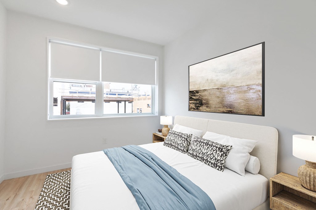 Minimalist bedroom with a comfortable bed, large abstract artwork above, and a neutral color palette creating a serene atmosphere.