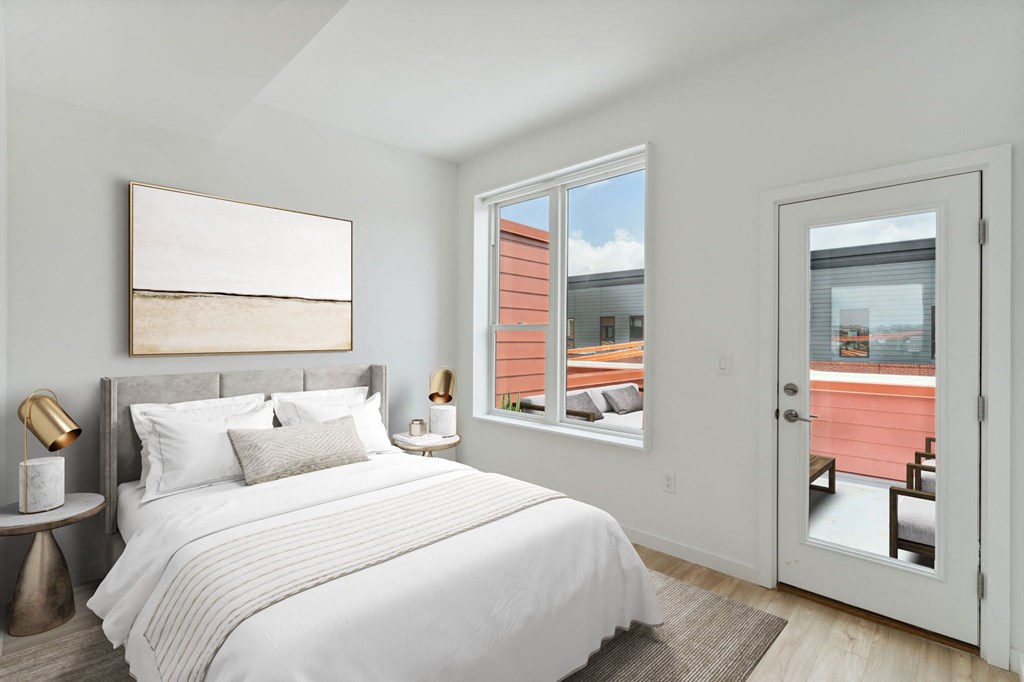 Compact bedroom with a comfortable bed with navy and white bedding, plush pillows, a white fluffy rug, and a plant by the window, creating a serene and inviting atmosphere.