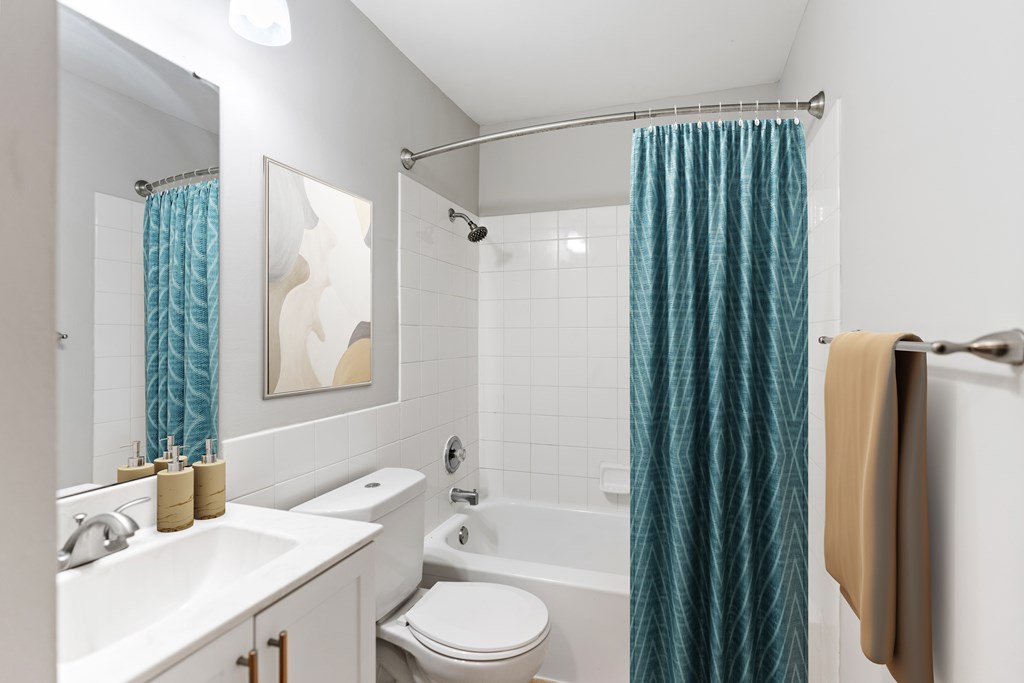 A bathroom with a white sink, toilet, and bathtub with a blue shower curtain.