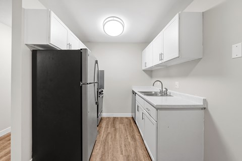 A kitchen with a black refrigerator and white cabinets.