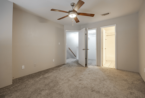 A room with a ceiling fan and carpeted floor.