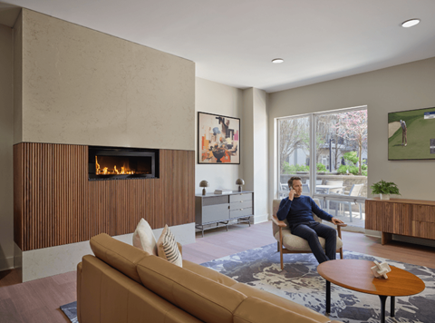 A man is sitting in a chair in a room with a fireplace.