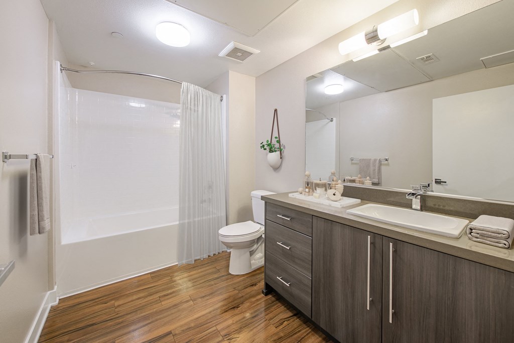 A bathroom with a toilet, sink, and mirror.