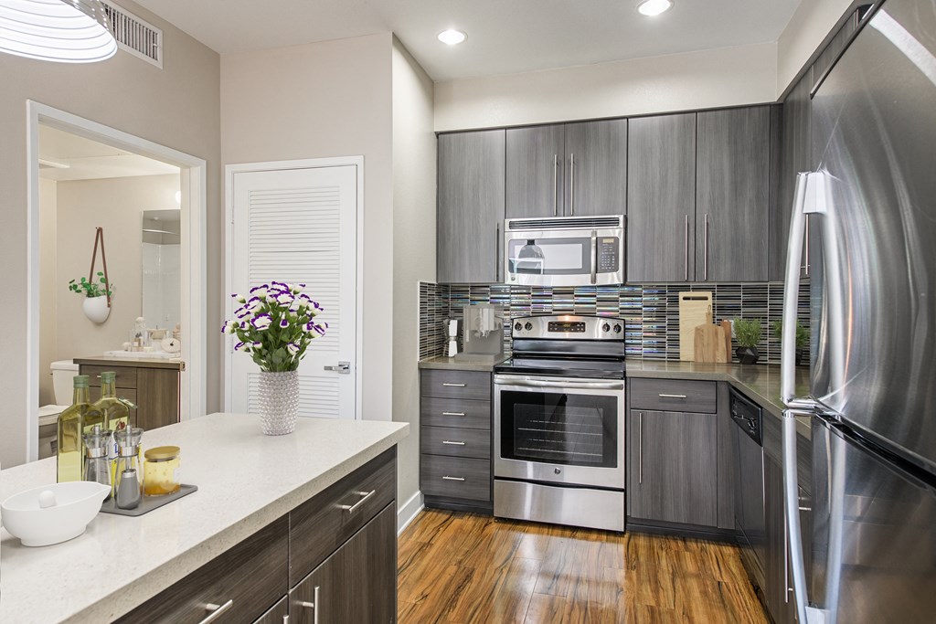 A modern kitchen with stainless steel appliances and wooden floors.
