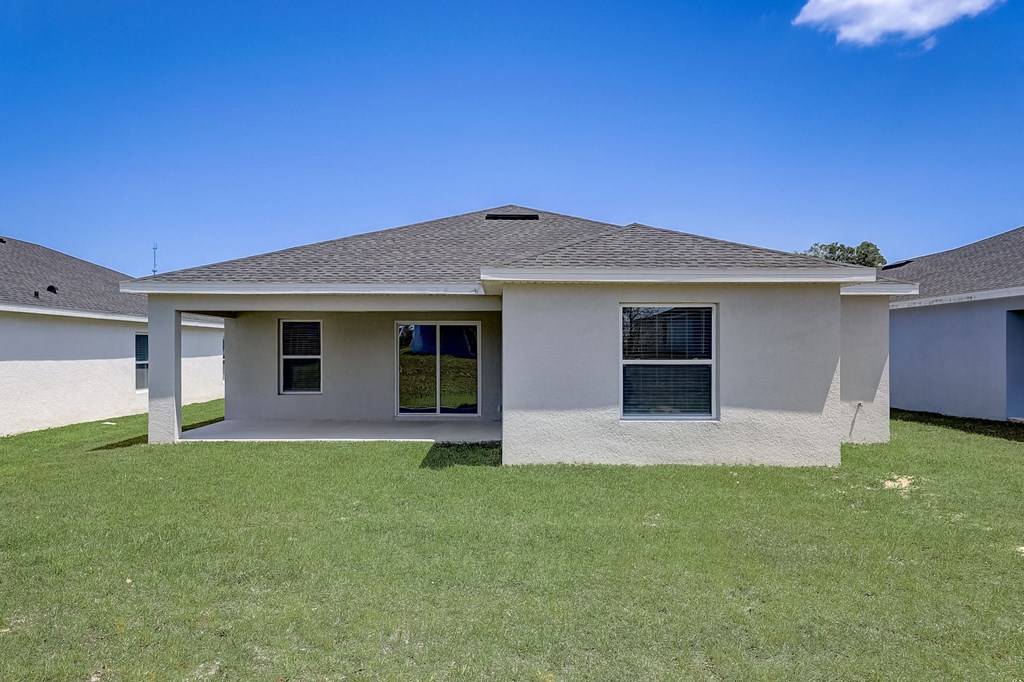 House with a yard under a clear blue sky at The Groves at Lake Ella in Lady Lake, Florida, a pet-friendly rental community.