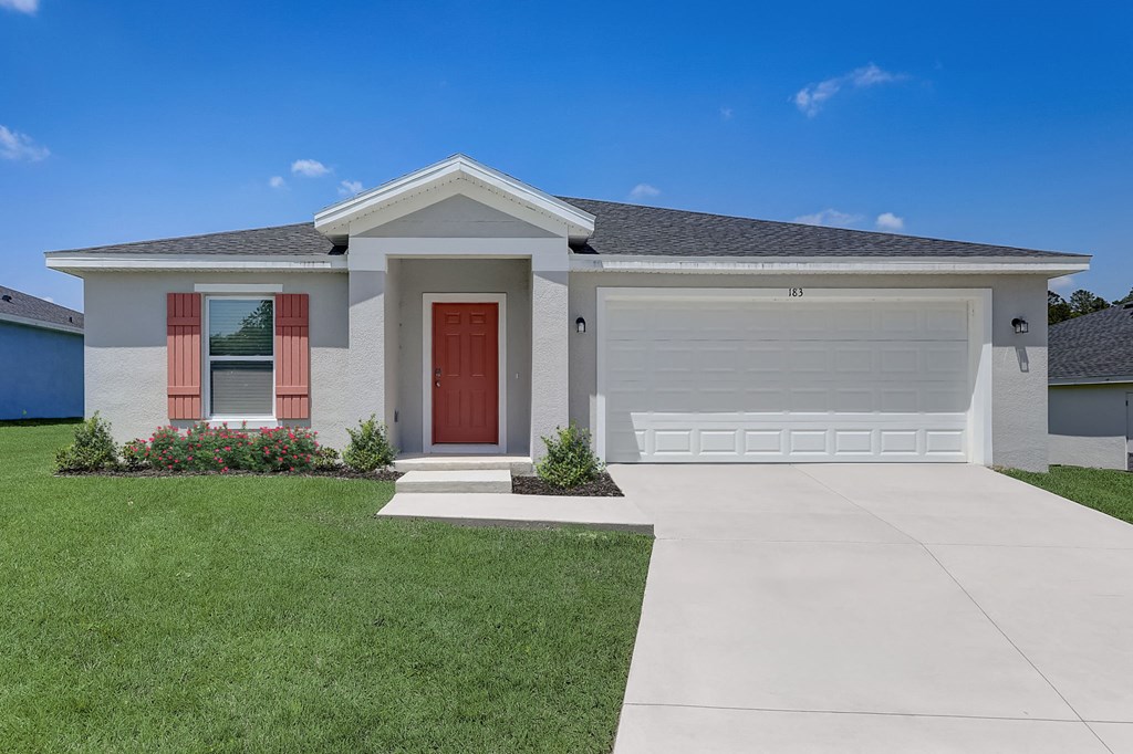 House with a garage and well-maintained lawn at The Groves at Lake Ella in Lady Lake, Florida, a pet-friendly rental community offering convenience for residents.