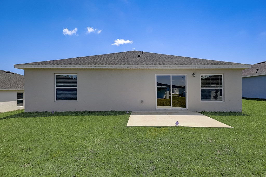 House with sliding windows and a spacious backyard at The Groves at Lake Ella in Lady Lake, Florida, a pet-friendly rental community.