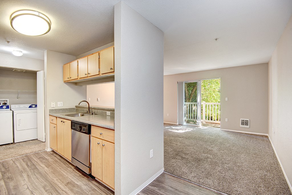 a kitchen and living room with a sliding glass door leading to a balcony