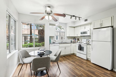 A kitchen with white appliances and a table with chairs.