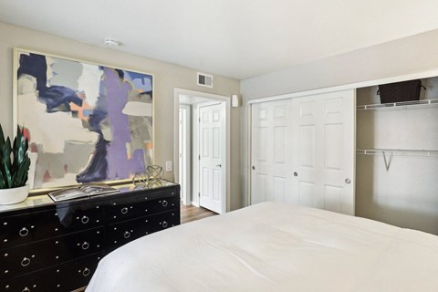 A bedroom with a large bed and a painting on the wall.