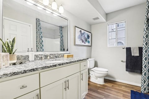 A bathroom with a marble countertop and white cabinets.