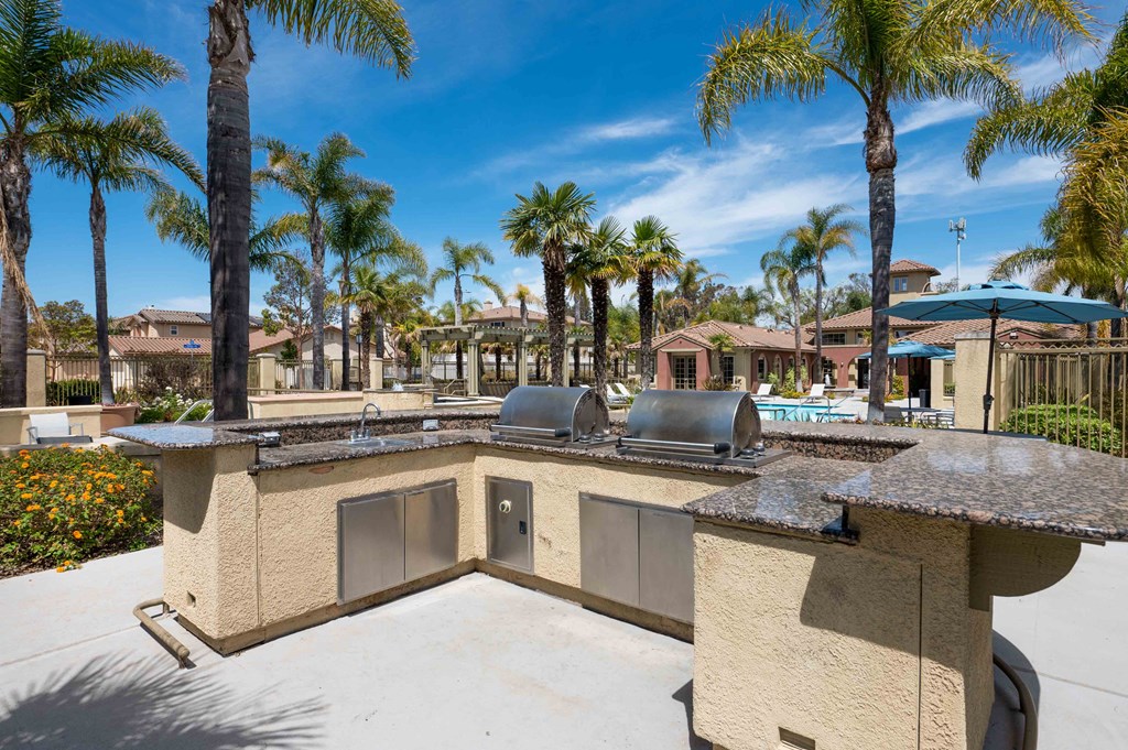 an outdoor kitchen with a pool and palm trees