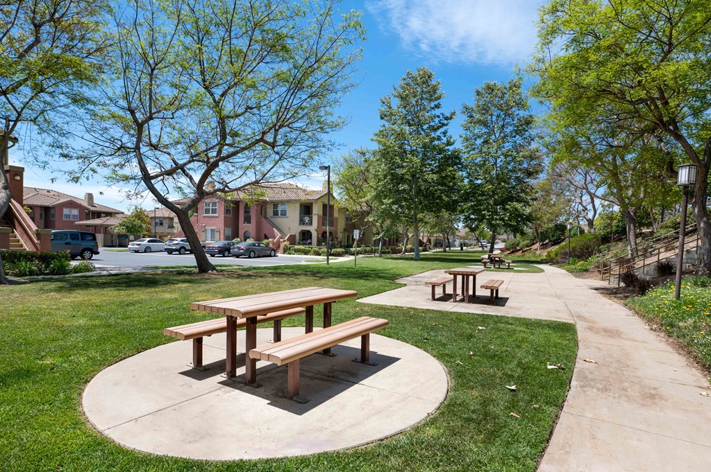 two picnic tables on a sidewalk in a park