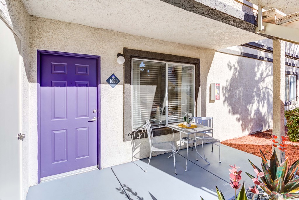 a patio with a purple door and a table and chairs
