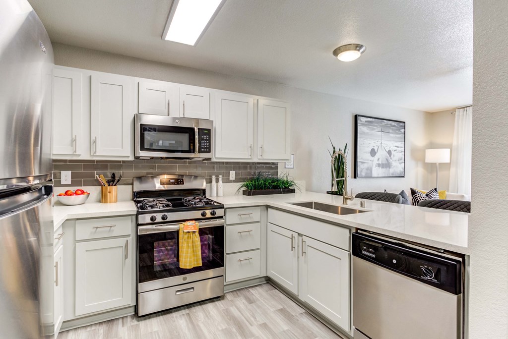 an open kitchen with stainless steel appliances and white cabinets