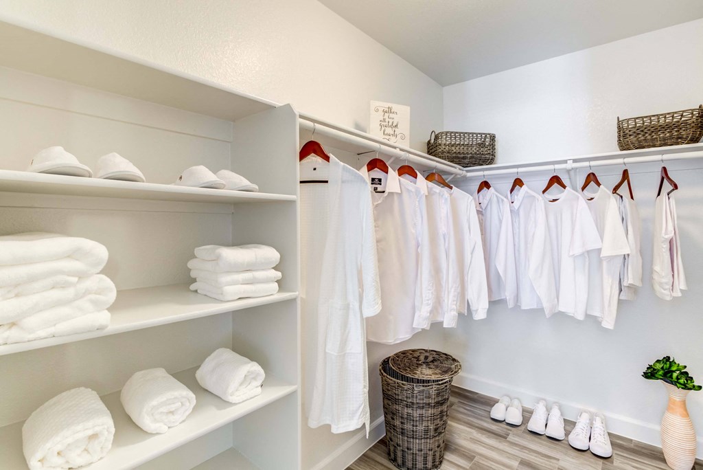 a walk in closet with white towels and hangers