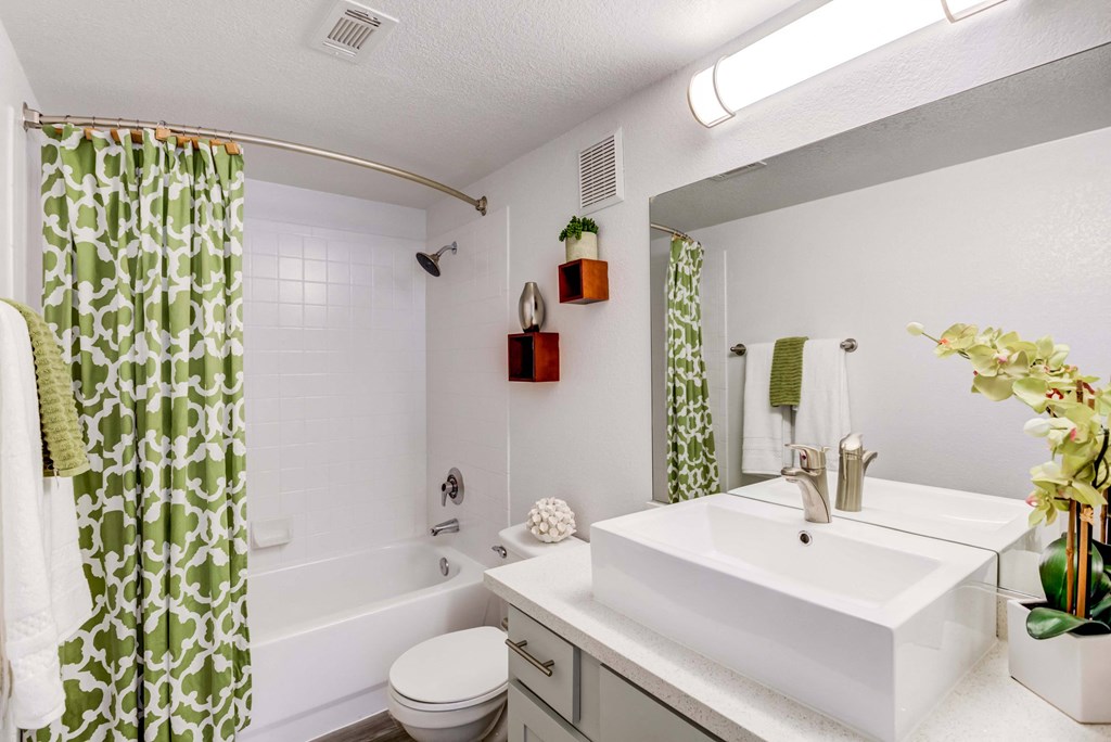 a white bathroom with a green and white shower curtain