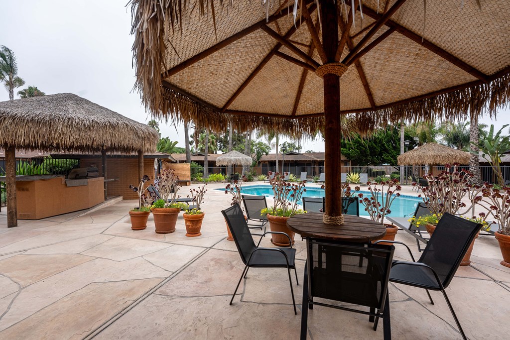 a patio with a table and chairs and a pool in the background