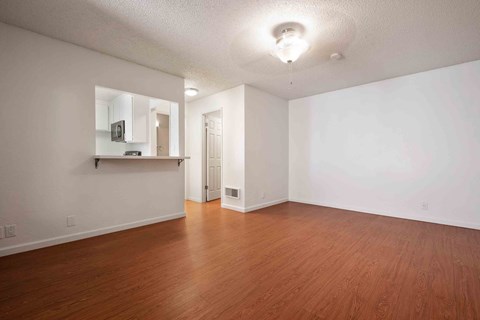 an empty living room with wood floors and white walls