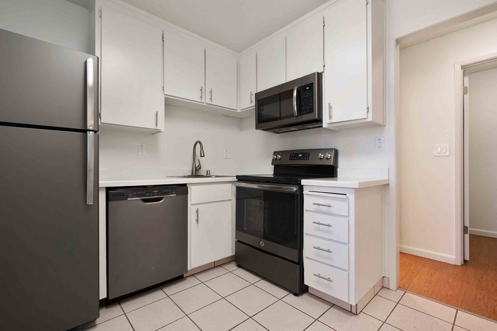 Apartments In San Jose, CA - Village of Taxco - Kitchen With Tile-Like Flooring, White Cabinets, And Stainless Steel Appliances