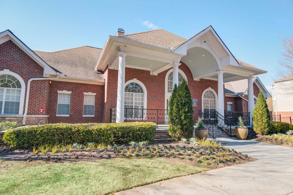 the front of a brick house with a porch and a driveway