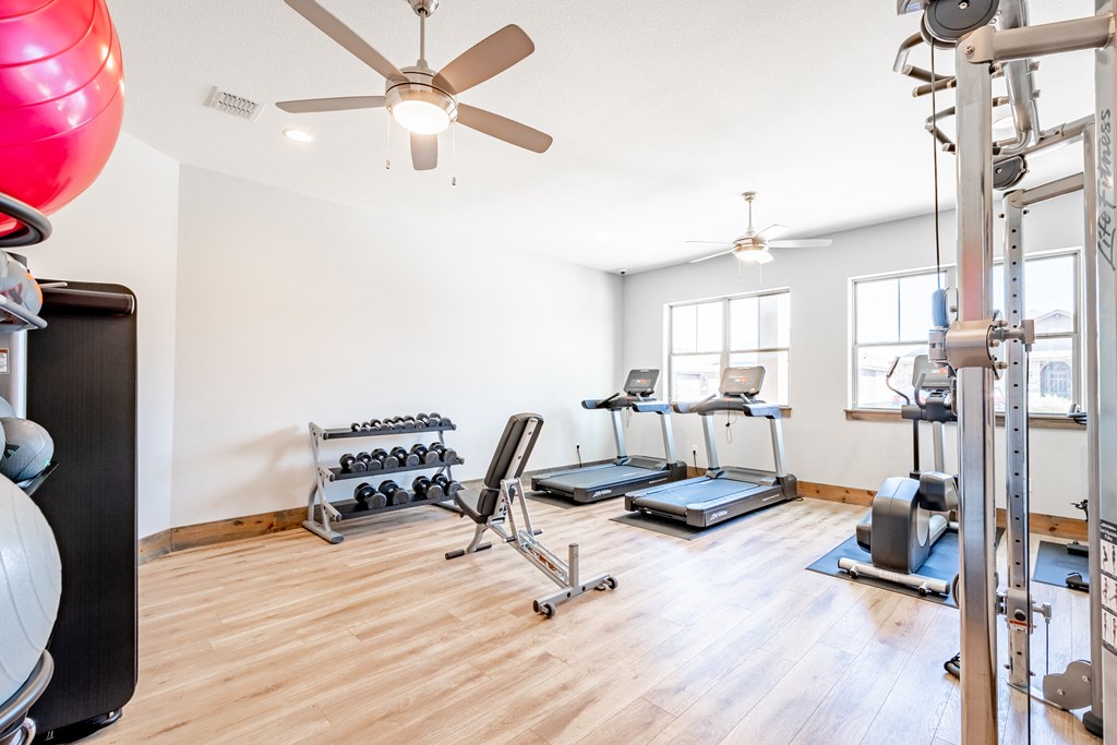 the home gym has plenty of exercise equipment and a ceiling fan