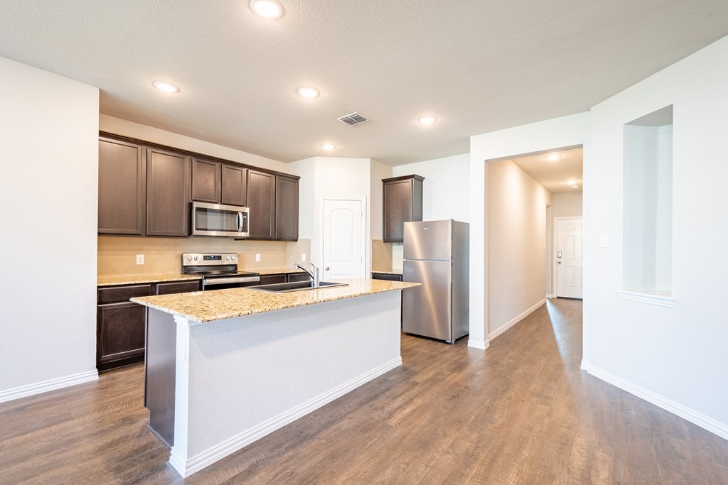 a kitchen with a large island and a stainless steel refrigerator