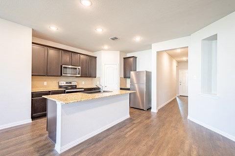 a kitchen with a large island and a stainless steel refrigerator