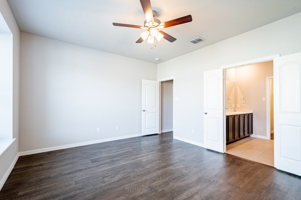 an empty living room with a ceiling fan and a bathroom