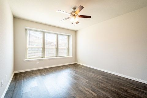 an empty living room with wood floors and a ceiling fan