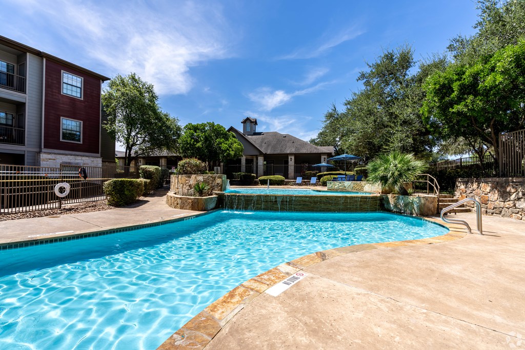 A swimming pool surrounded by a fence and trees.