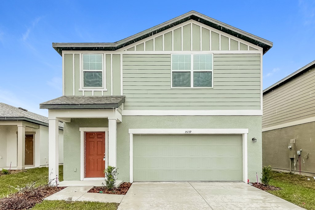 A two-story house with a garage door and a brown door.