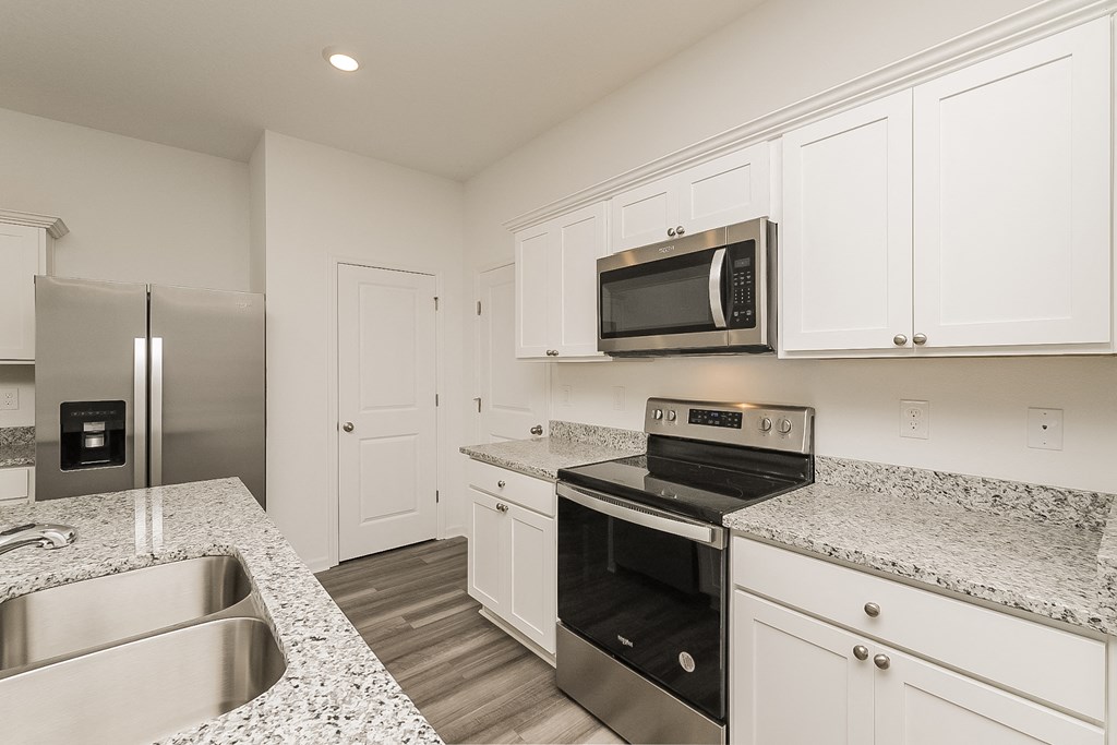 A kitchen with a stainless steel refrigerator, microwave, oven, and sink.