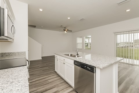 A modern kitchen with a stainless steel dishwasher and a ceiling fan.
