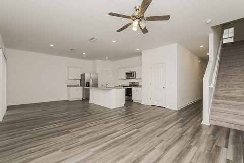 A spacious room with a ceiling fan and wooden flooring.