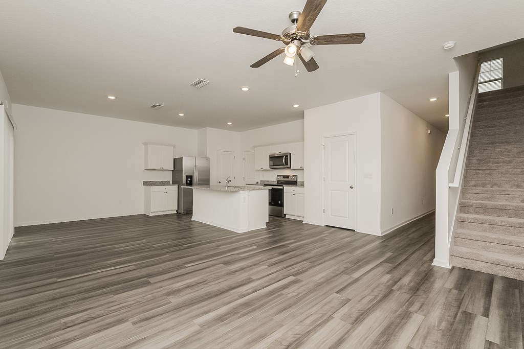 A spacious room with a ceiling fan and wooden flooring.