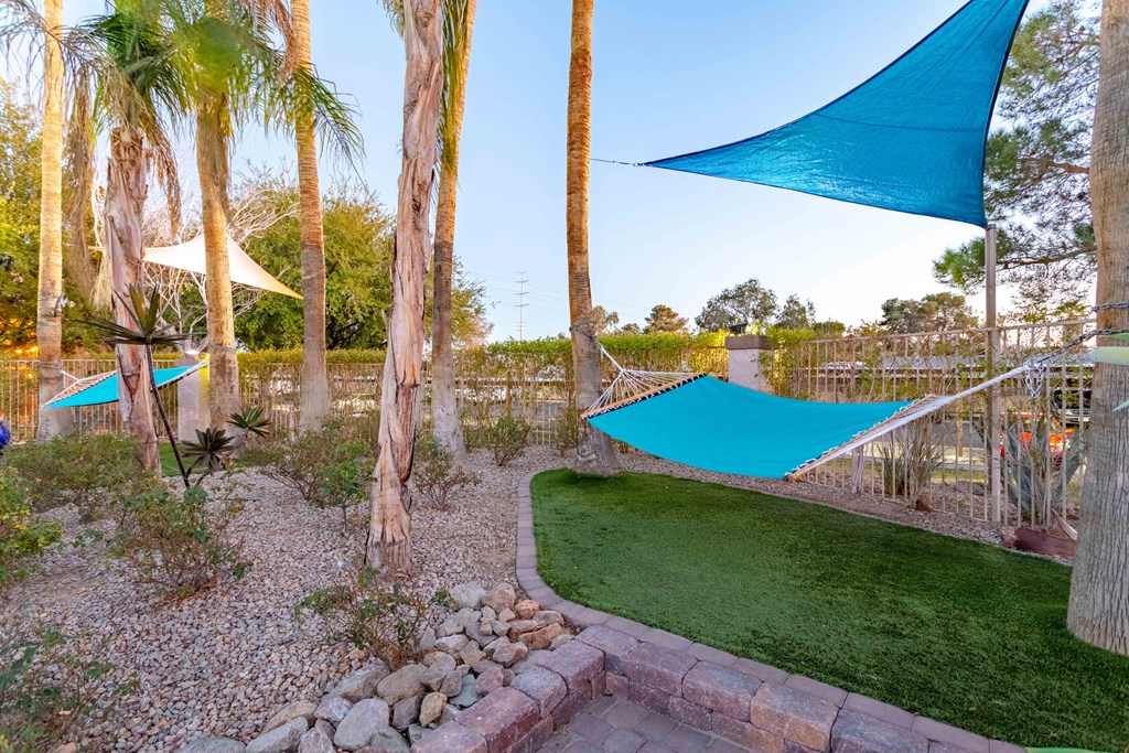 a backyard with hammocks and artificial turf and palm trees