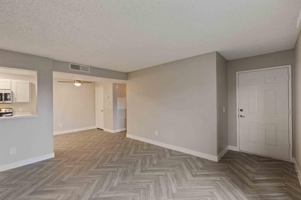 an empty living room and kitchen with a wood floor