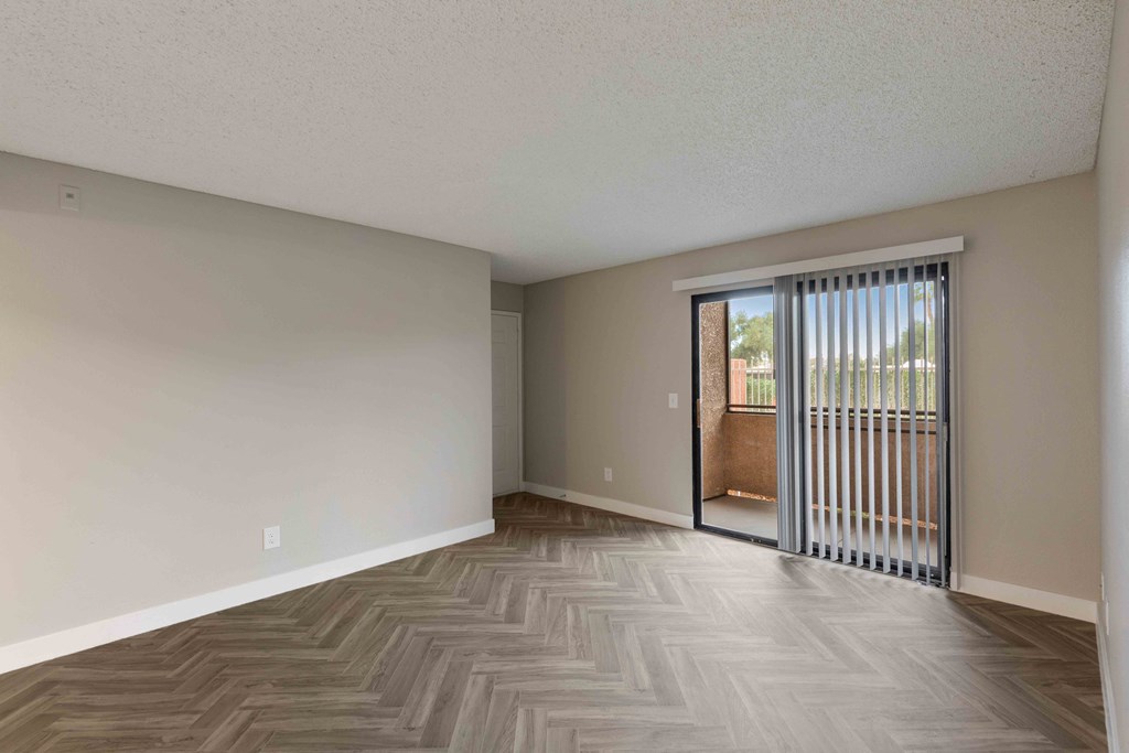 an empty living room with a sliding glass door to a balcony