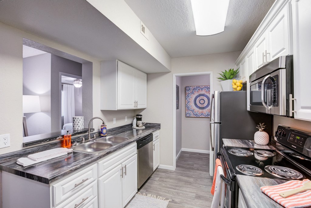an open kitchen with stainless steel appliances and white cabinets