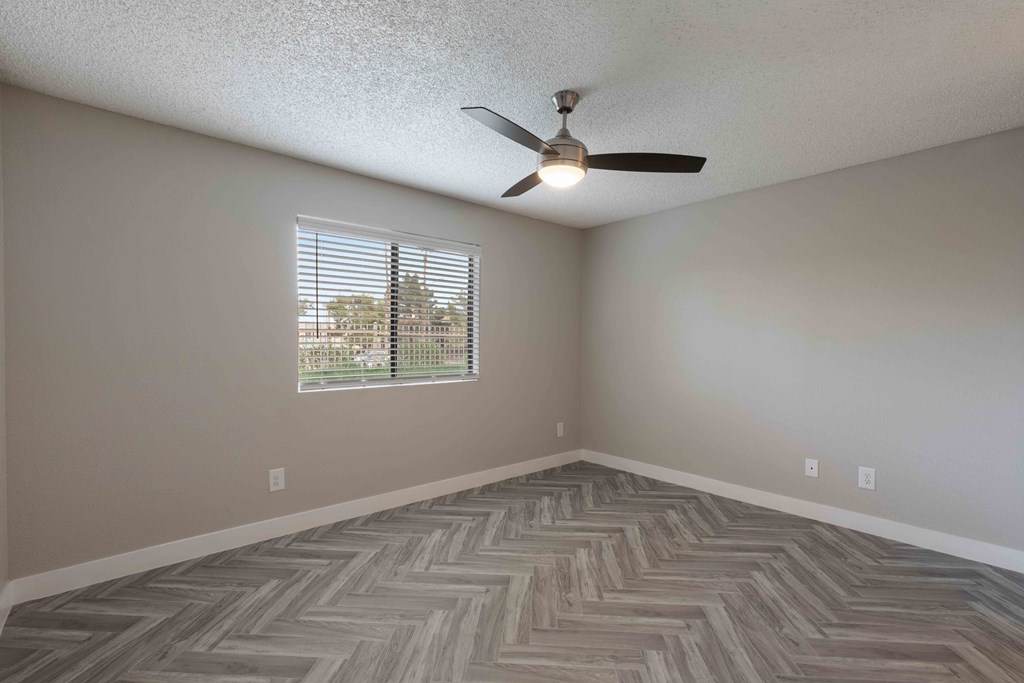 an empty living room with a ceiling fan and a window