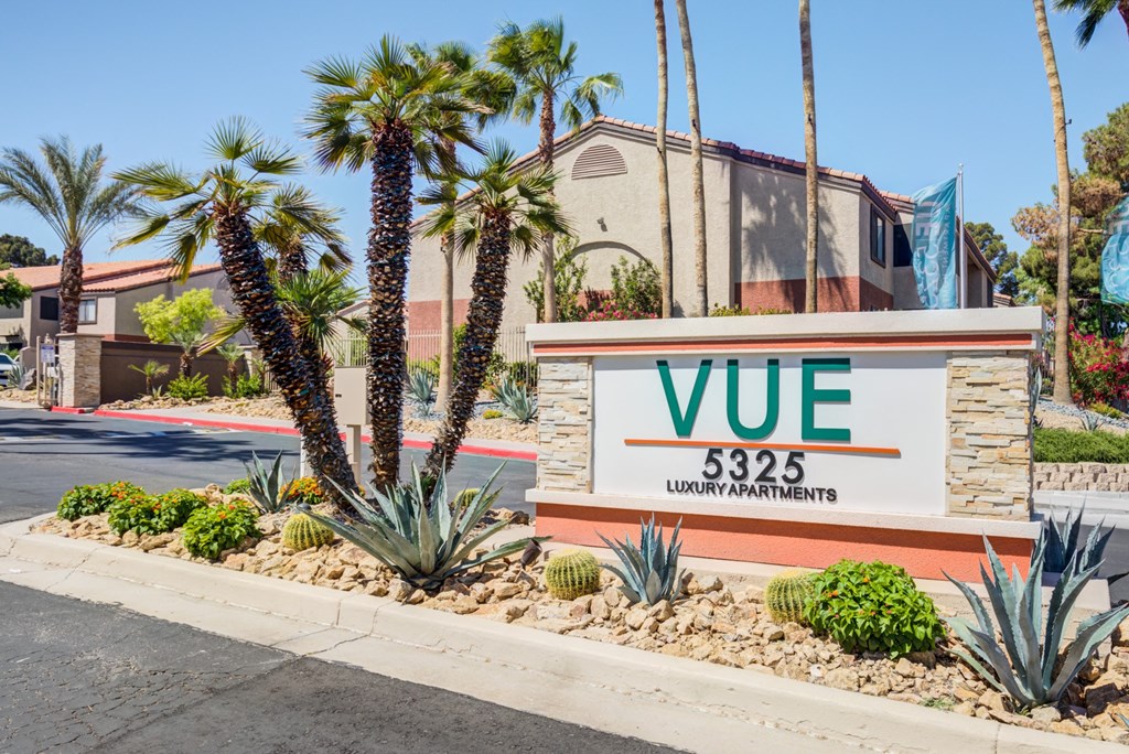 the vue apartments sign in front of a building with palm trees