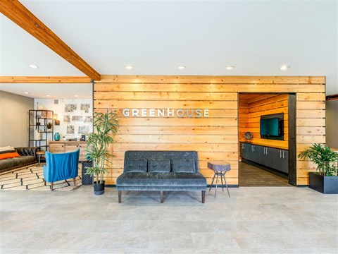 Apartments in South Seattle, WA with In-Unit Washer and Dryer - Greenhouse - Welcoming Lobby with Lounge Seating. View of Reception, Private Space with TV and Decorated with Potted Plants, and Wood Finishes.