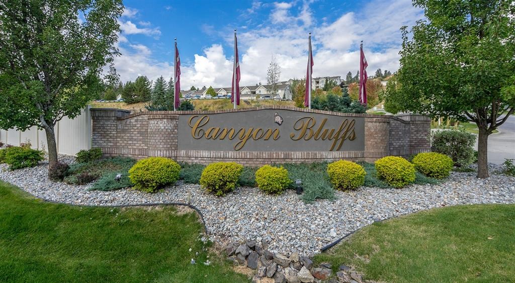 Apartments Spokane WA - Canyon Bluffs - Monument Sign Surrounded by Lush Landscaping and Flags