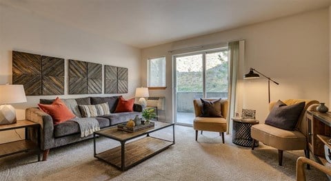 One Bedroom Apartments in Spokane WA - Canyon Bluffs - Living Room with Carpet flooring, A Sliding Door to the Balcony, and Modern Furniture