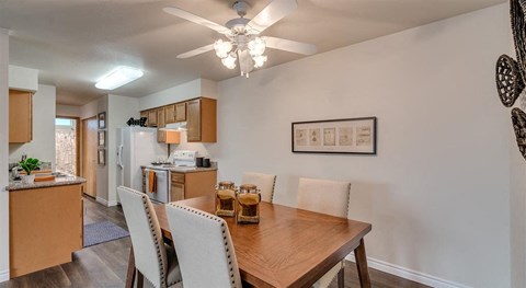 a kitchen and dining room with a wooden table and a ceiling fan
