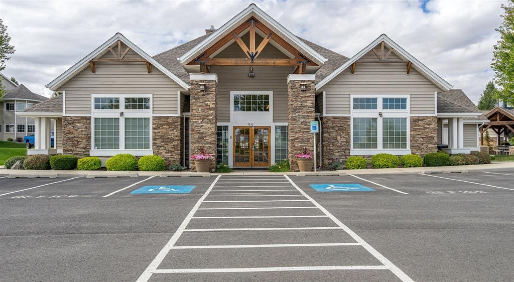 Apartments for Rent in Spokane - Deer Creek - Building Exterior of Clubhouse with Lush Landscaping and View of Parking Lot