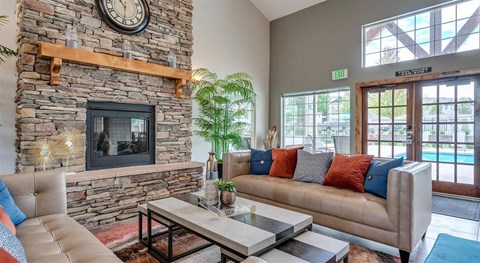 a living room with couches and a fireplace and a clock on the wall